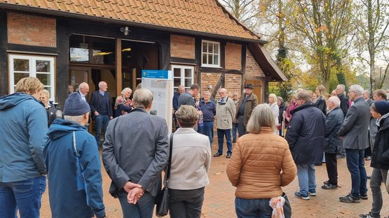 Zahlreiche Menschen stehen im Kreis um die Geschichts- und Erinnerungstafeln. Im Hintergrund ein Fachwerkhaus.